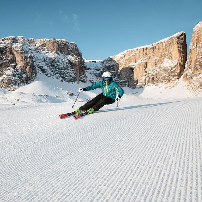 Man skiing on a prepared slope in a winter landscape with mountains